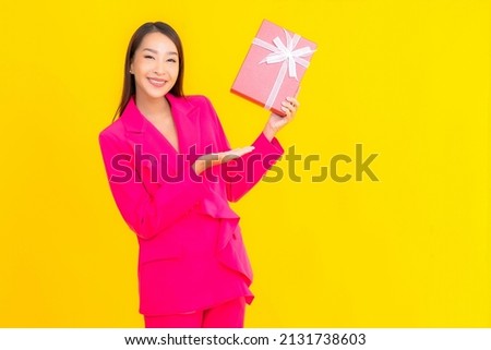 Portrait beautiful young asian woman with red gift box on yellow color isolated background