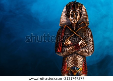 metal pharaoh statue on a blue background with smoke. High quality photo