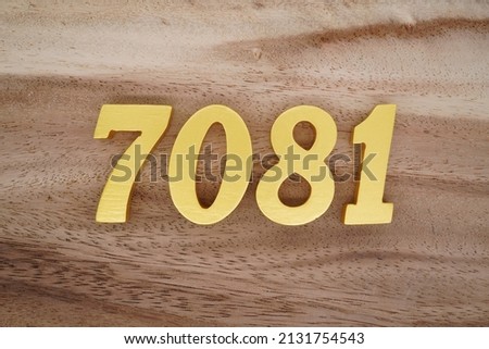 Wooden  numerals 7081 painted in gold on a dark brown and white patterned plank background.