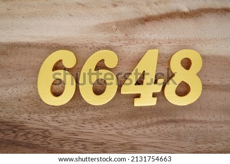 Wooden  numerals 6648 painted in gold on a dark brown and white patterned plank background.