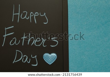 happy father’s day greetings handwritten on blackboard decorated with blue heart
