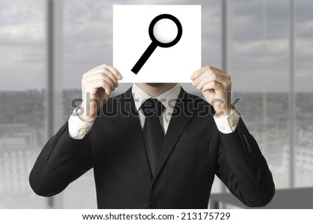businessman in black suit  hiding face behind sign loup magnifier