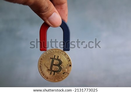Concept of cryptocurrency. Hand holding magnet and attract bitcoin. Cryptocurrency mining.