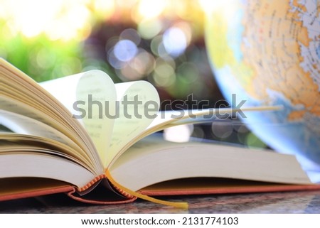 The book opens, and the book page rolls into the heart colorful background selective focus and with a very shallow depth of field  Royalty-Free Stock Photo #2131774103