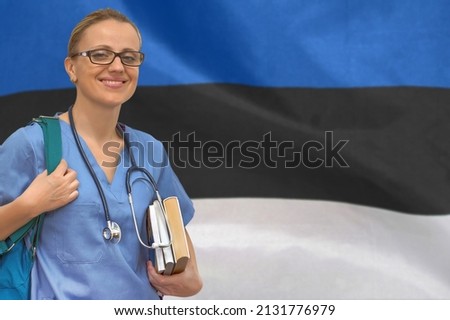 Female student doctor with stethoscope and books in hand on the Estonia flag background. Medical education concept. Medical learning in Estonia