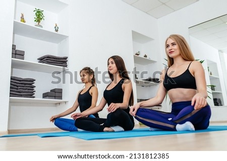 Three girls are doing yoga in the studio.