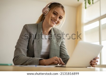 Young woman working at home with laptop and papers on desk and headphones.  Home office concept. Gray notebook for working. High quality photo