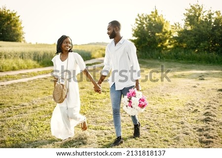African newlyweds walking with bouquet in nature