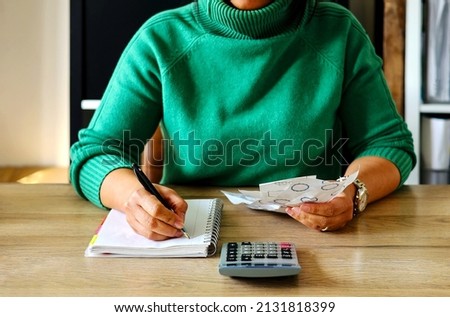 Young Asian housewife doing home income outcome accounts holding receipts from supermarket with calculator, upset by rising grocery prices and surging cost  as an inflation financial crisis. Royalty-Free Stock Photo #2131818399