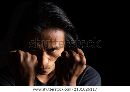 Man with anger expression looking for a fight. best for anger, mad, frustration, depression, and fighting background. lowkey photography technique. Suitable for motivational background. 