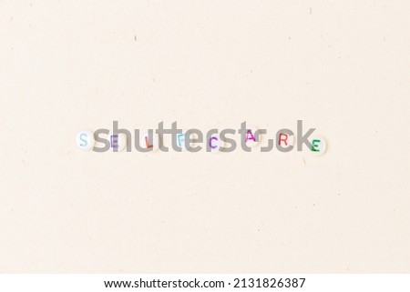 Self care. White round beads with colorful letters on a beige background.