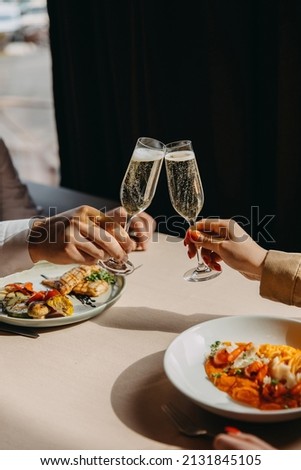 Closeup of a man and woman clinking glasses with champagne at a restaurant. Royalty-Free Stock Photo #2131845105