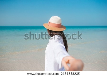 Woman on the beach following by hand