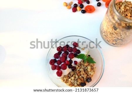Healthy breakfast bowl with homemade granola. proper nutrition bowl of oat granola with yogurt, fresh raspberries, blueberries, strawberries, blackberries nuts with spoon on white for healthy food.