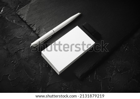 Photo of blank business cards, pen, usb flash drive and slate plate on black stone background. Branding mock up.