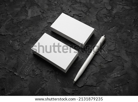 Blank business cards and pen on black stone background. Mockup for branding identity. Template for graphic designers portfolios.