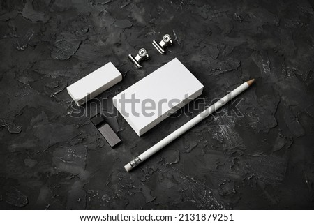 Blank corporate identity on black stone background. Photo of blank business cards, pencil, eraser, usb flash drive and clips.