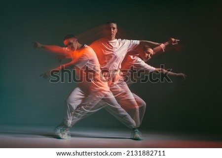Dancing young girl moving in expressive hip hop dance. Dancer in red studio light. Long exposure. Breakdancing school ad Royalty-Free Stock Photo #2131882711