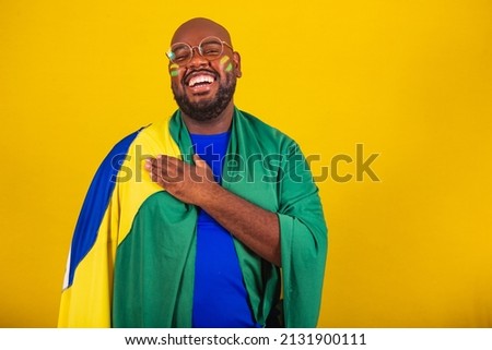 handsome afro brazilian man wearing glasses, brazilian fan, brazil, world cup 2022, hand to chest, singing anthem is born. Brazilian music. beloved homeland. patriot. Royalty-Free Stock Photo #2131900111