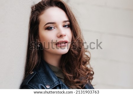 Portrait of young woman with curly hair looking at camera in the city