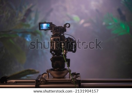Video production backstage. Behind the scenes of creating video content, a professional team of cameraman with a director filming commercial ads. Video creation industry. Jungle forest background.
