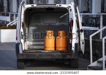 Orange gas cylinders transported inside a pickup car. Gas butane bottles in truck ready for delivery. Vehicle delivering hazard goods with compressed gas. Royalty-Free Stock Photo #2131905607