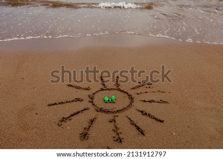 memes. vacation by the sea. Recreation and tourism on the sea coast. The symbol of the family and the sun is painted on the sand near the waves of the sea.