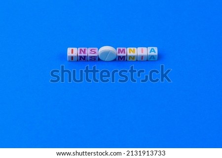 INSOMNIA text made in cubes, a white medical pill with a score instead of the letter O. Classic traditional blue background.