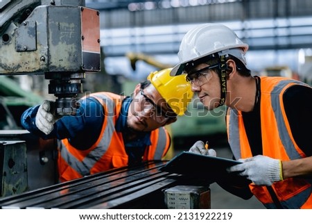 Factory mechanics or Engineers repair and inspect the operation of large metal drilling machines in the steel processing plant. Royalty-Free Stock Photo #2131922219