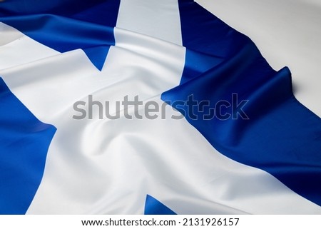 Rippled flag of Scotland lying on white surface