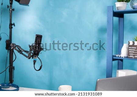 Focus on professional microphone swivel boom arm stand in empty podcast transmission studio used for online radio station streaming. Detail of audio live broadcast desk setup with digital mic.
