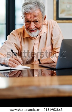 A senior student writing down homework and looking at the camera. Senior on retraining program. Royalty-Free Stock Photo #2131953863
