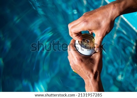 Selective focus white beer can in hand. Man is soaking in the pool with an open beer can relax and enjoy the holidays. Royalty-Free Stock Photo #2131957285