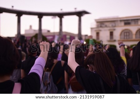 Young women raising their fist in protest against violence, for women's empowerment, feminism, freedom, gender equity, sorority. Royalty-Free Stock Photo #2131959087