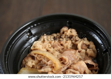 beef bowl in a plastic container placed on a wooden table