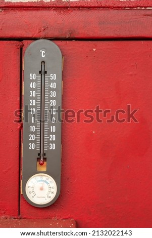 A traditional thermometer and Hygrometer, 2 in 1 device for measuring temperature and humidity level which is installed on metal red wall of goods container. Industrial equipment object photo.