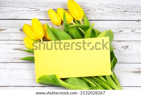 Top view photo yellow tulips and envelope on the wooden background, copy spce