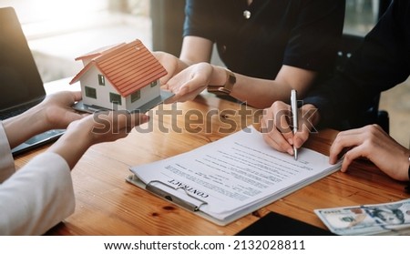 Real estate agent offer hand for customer sign agreement contract signature for buy or sell house. Happy asian couple signing a contract together at office. Real estate contact agreement concept