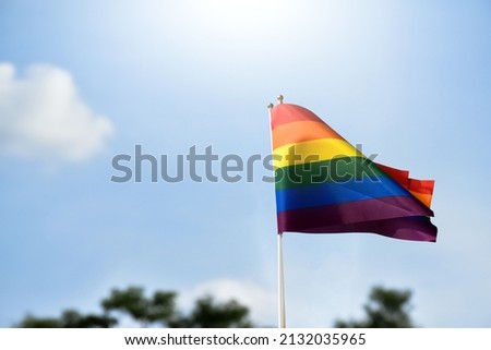 Rainbow flag, a symbol for the LGBT community, waving in the wind with a cloudy bluesky background. 