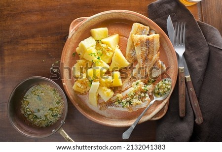 Fish dish - fried cod fillet with boiled potatoes on wooden table.  Mediterranean food with fillet fish