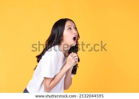 Image of feeling excited, shock, surprise and happy. Young asian woman standing on yellow background. Female face expressions and emotions body language concept. Royalty-Free Stock Photo #2132044595