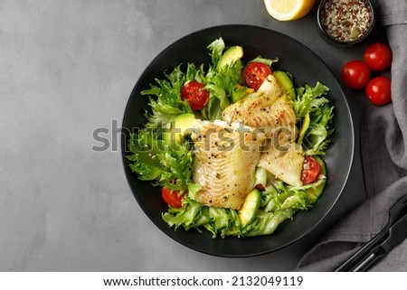 Dish with salad with white sea fish, avocado and cherry tomatoes. Copy space.