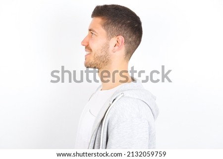 Profile of smiling young caucasian man wearing casual clothes over white background with healthy skin, has contemplative expression, ready to have outdoor walk.