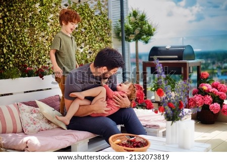 happy family, father and kids having fun, playing together on the rooftop patio on summer day