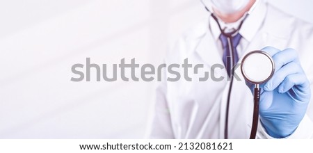 Stethoscope doctor medical background. Happy nurse in hospital uniform, blue gloves holding stethoscope isolated on white. Medicine service and healthcare concept Royalty-Free Stock Photo #2132081621