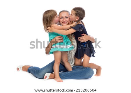 Two little daughters kiss Mom in the studio on a white background.