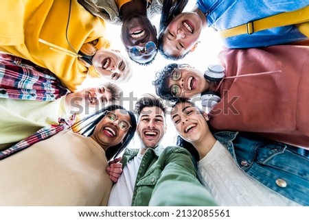Multiracial group of young people standing in circle smiling at camera - International teamwork students hugging together - Human resources and youth culture concept