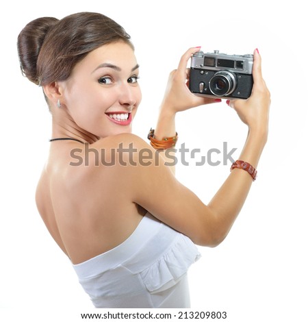 Beautiful excited girl takes picture with retro photo camera, over white.