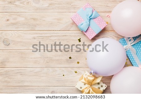 Holiday background with colorful balloon, gift and confetti. Flat lay style. Birthday or party greeting card with copy space.