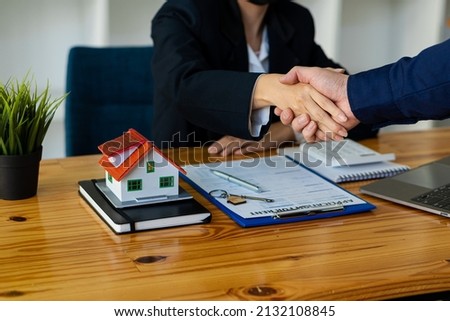 A handshake between the sales representative and the landlord when signing a home purchase or rental contact on the table. moving concept Real estate agents and clients join hands to celebrate finaliz